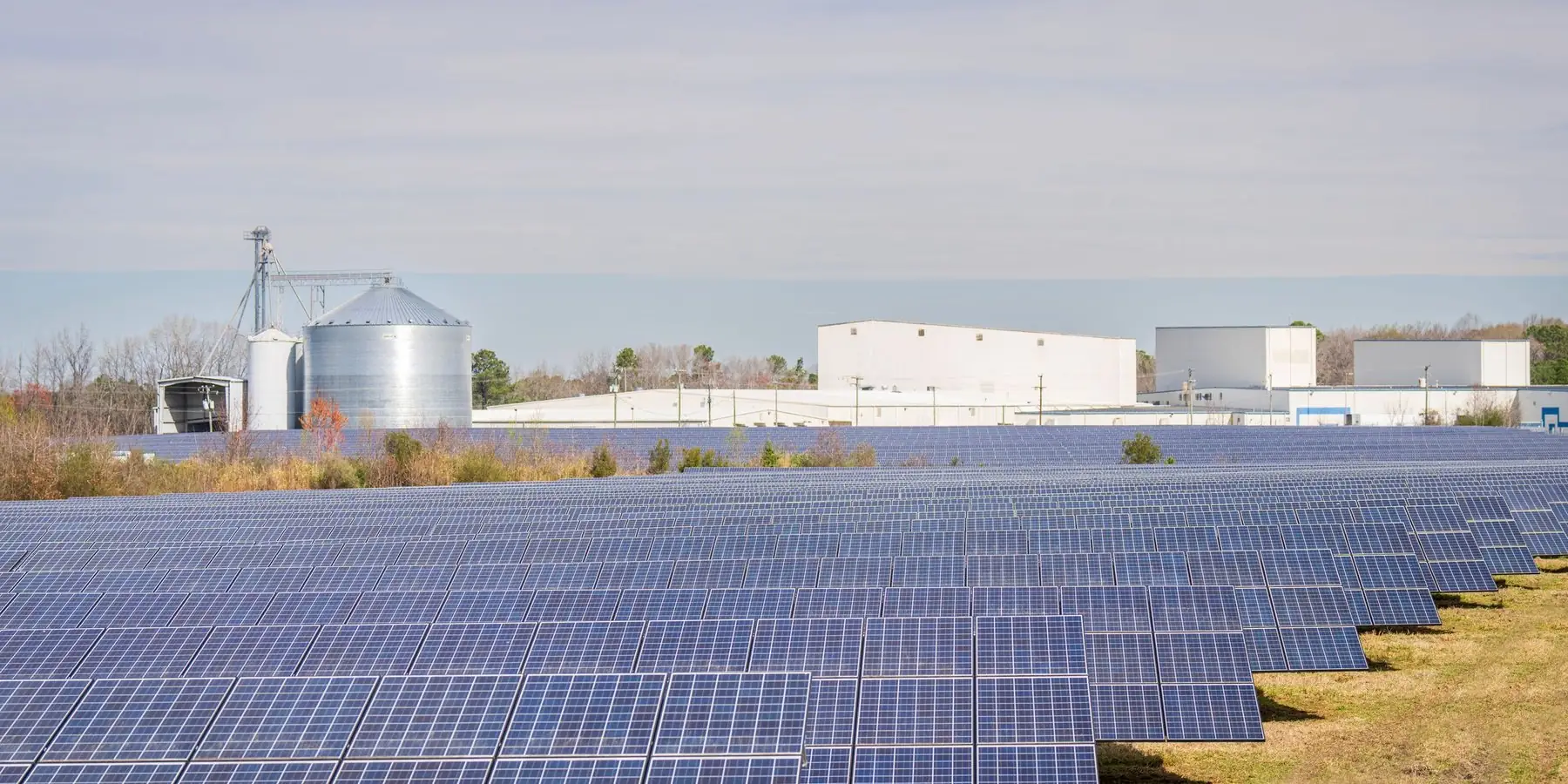 Campo con paneles solares y silos al fondo