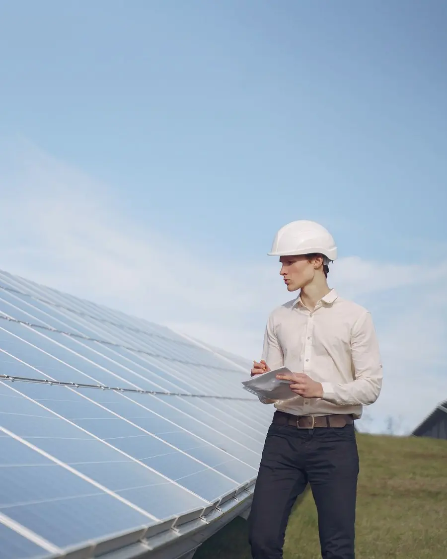 Ingeniero con casco tomando notas junto a una fila de paneles solares