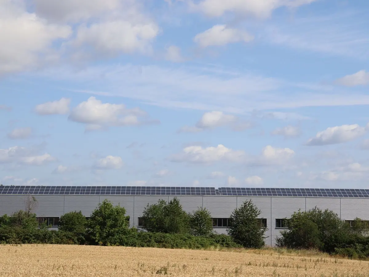 Nave logística con paneles solares junto a un campo de trigo